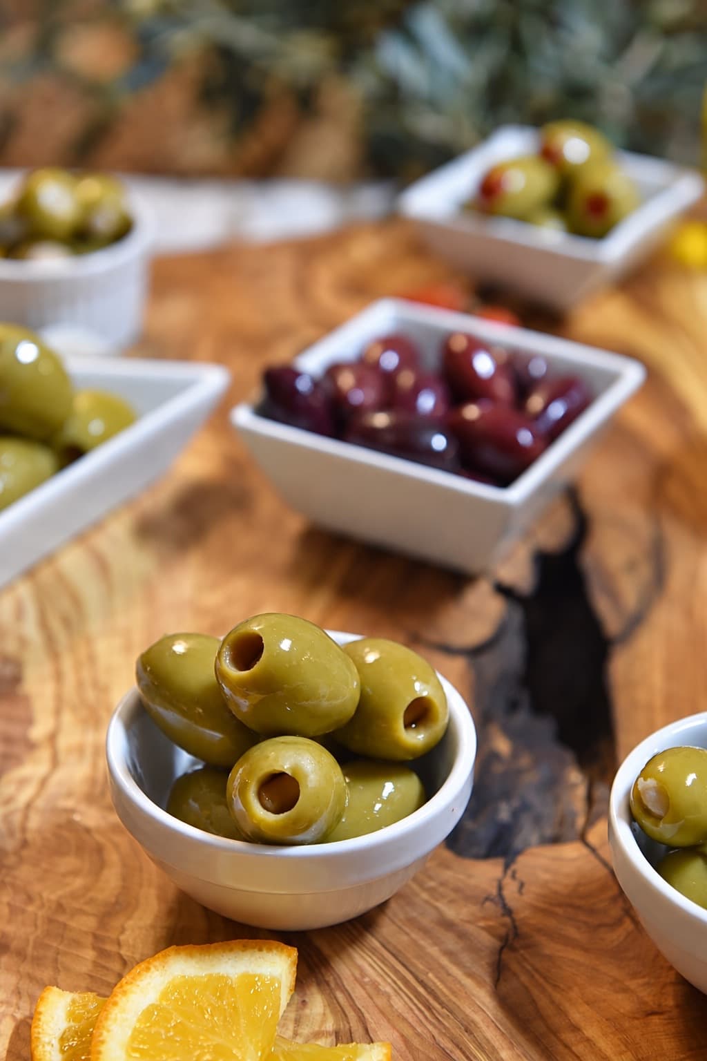 Ciotole di olive ripiene e olive Kalamata su un tagliere di legno d’ulivo